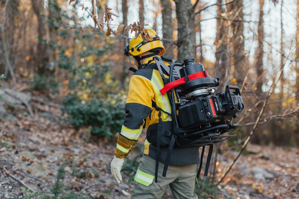 Bombero forestal transportando motobomba portátil ligera Vallfirest en el terreno